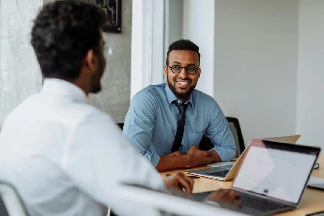 Professional team member working on laptop showing project planning interface with client consultation materials and friendly customer service setup